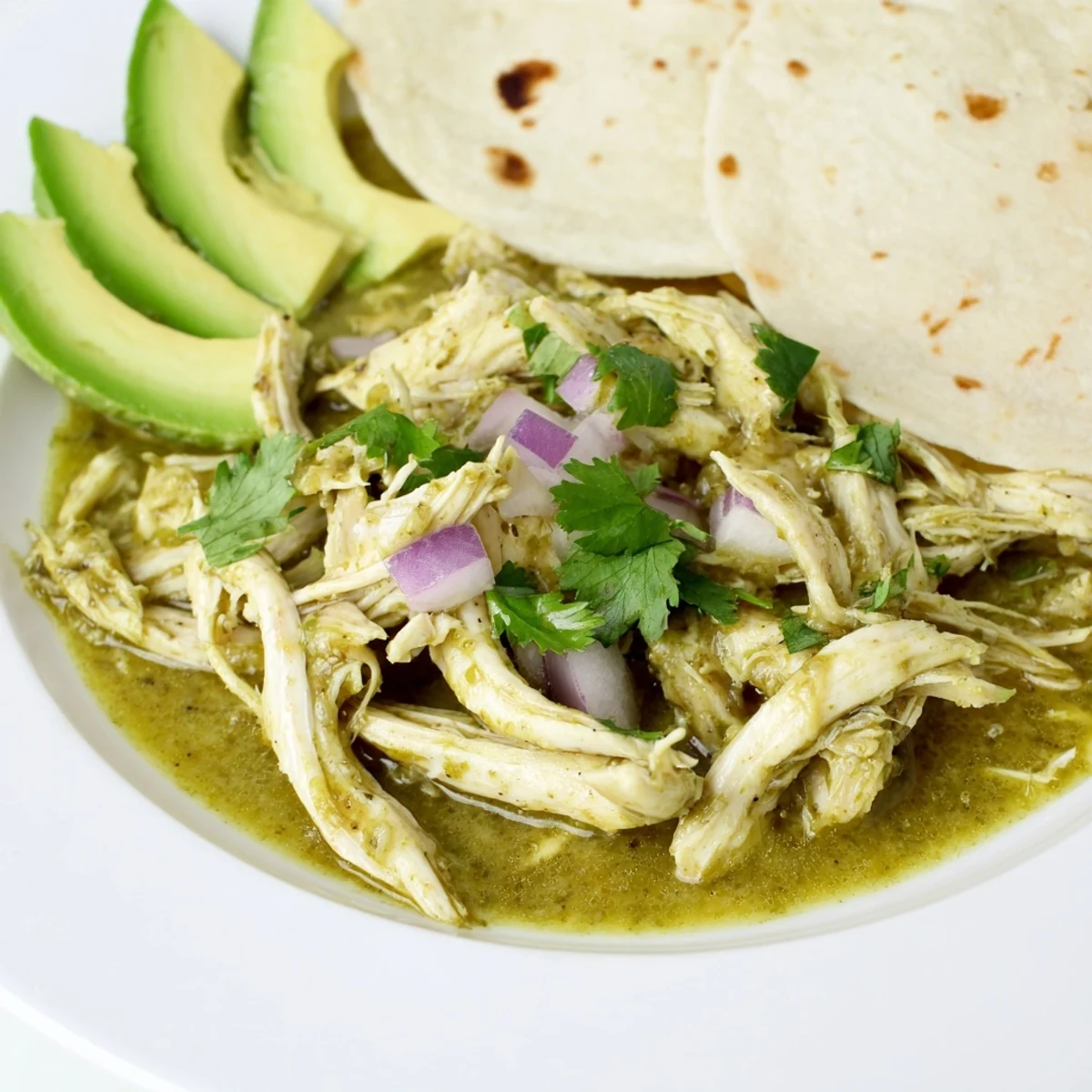 Golden chicken pieces simmered in vibrant green salsa verde sauce for Taco Tuesdays