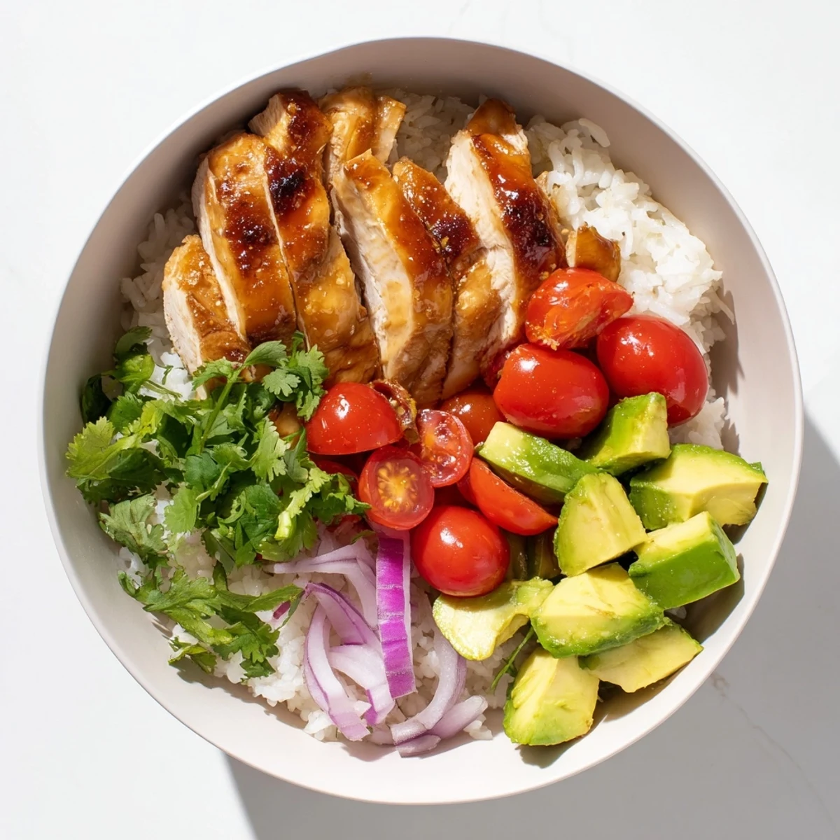 Golden honey lime chicken breast slices atop fluffy white rice with creamy diced avocado and fresh cilantro garnish
