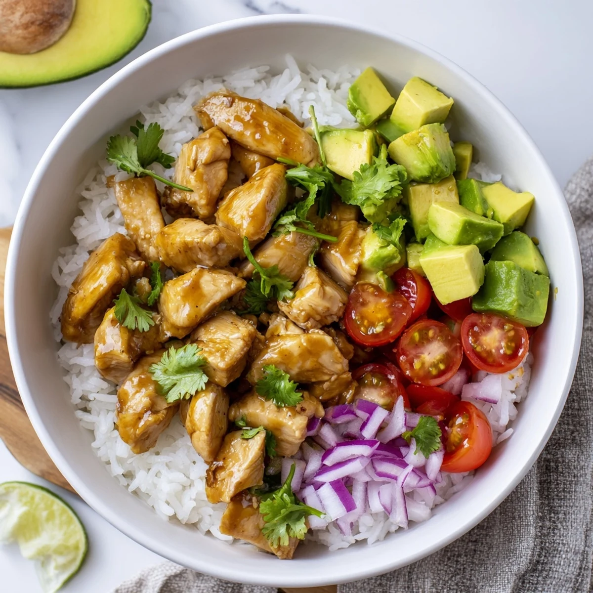 Vibrant rice bowl featuring marinated honey lime chicken, ripe avocado chunks, cherry tomatoes, and red onion
