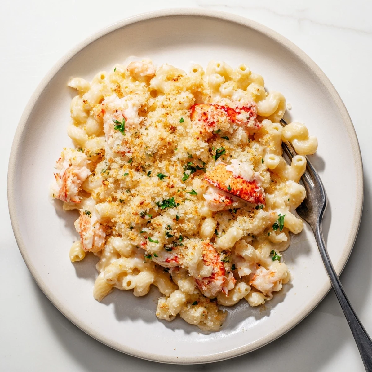 Succulent lobster pieces nestled in cheesy garlic butter pasta with golden breadcrumb crust