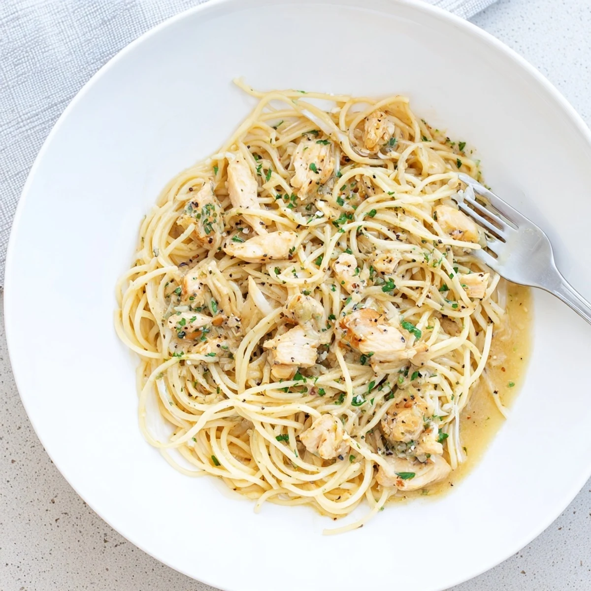 Shredded Crock Pot Angel Chicken atop angel hair pasta garnished with fresh parsley