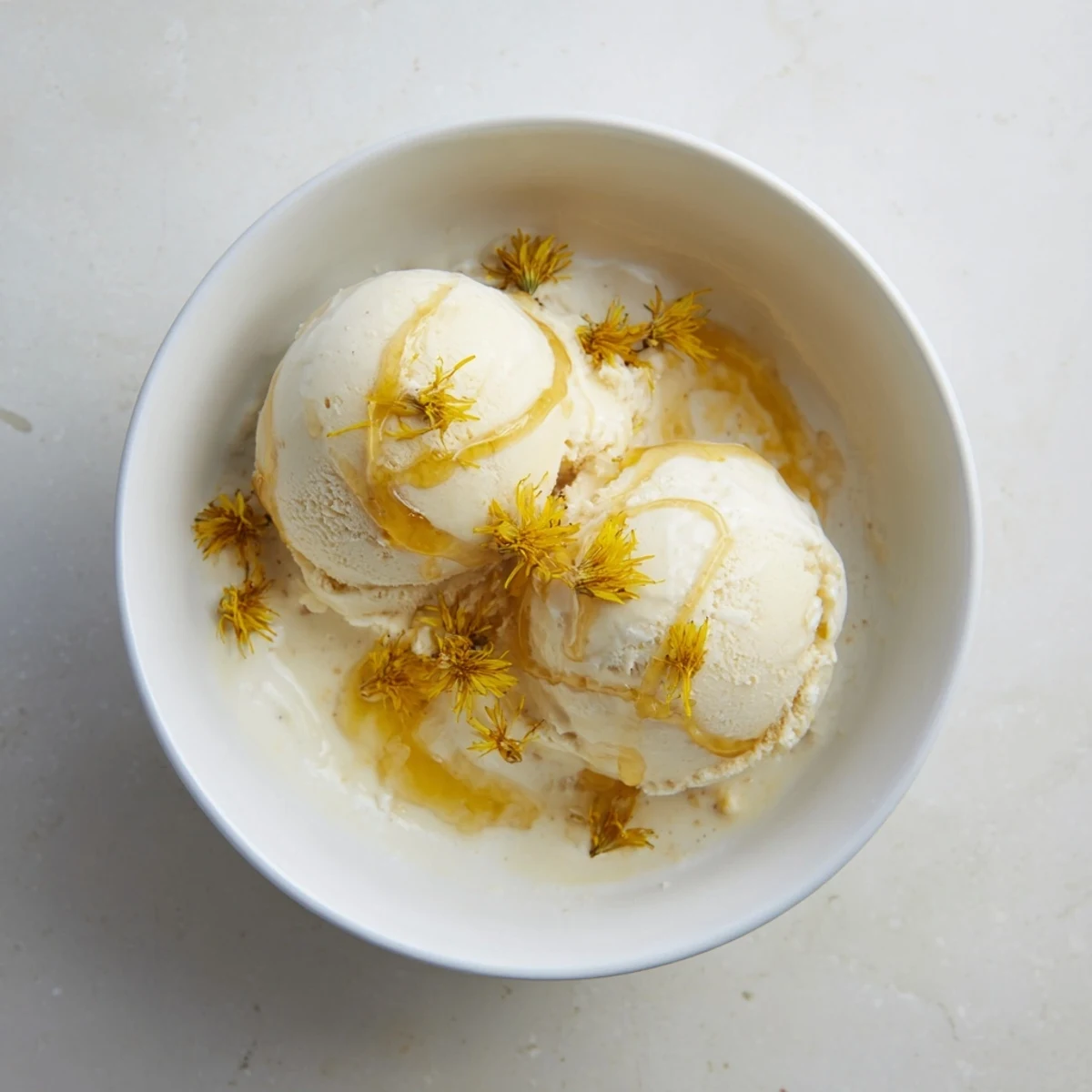 Creamy dandelion honey ice cream scoop garnished with golden petals and honey drizzle