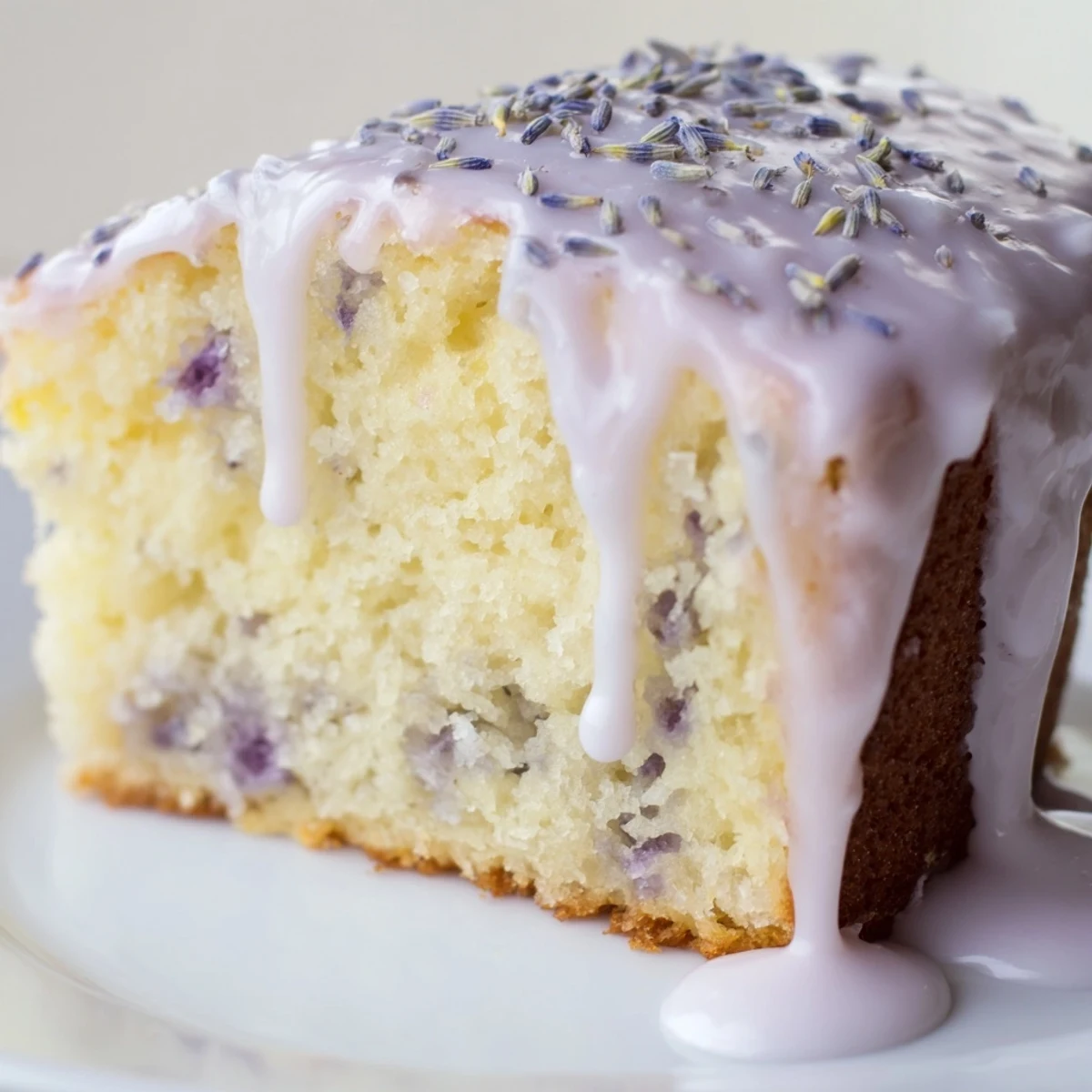 Lavender cake with lemon glaze drizzled over a tender golden crumb topped with purple buds