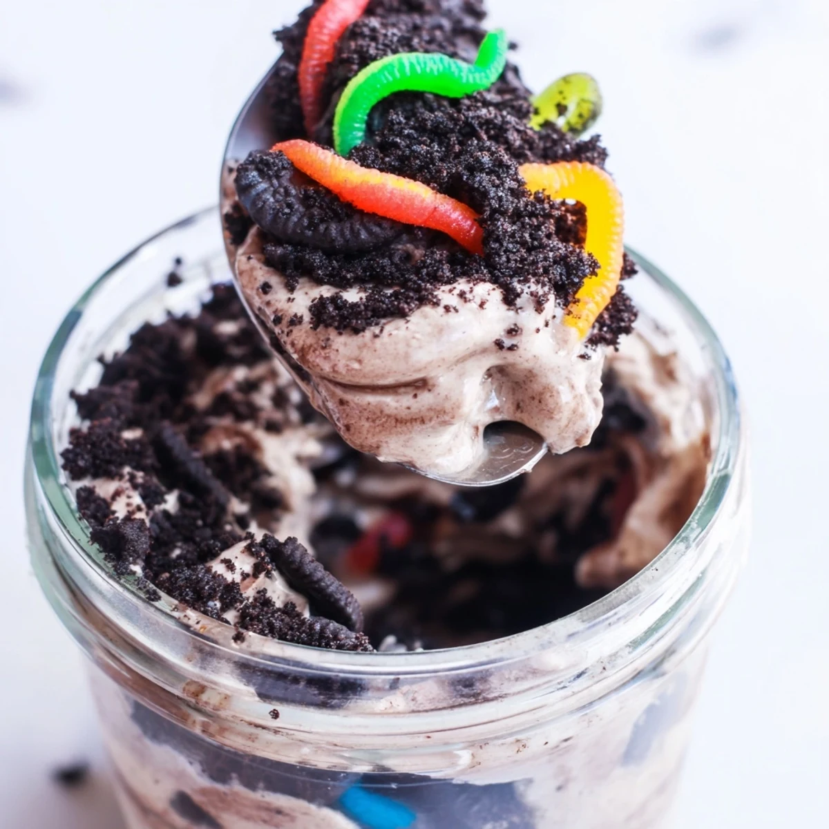 Chocolate dirt pudding layered in jars with Oreo crumbs and candy worms