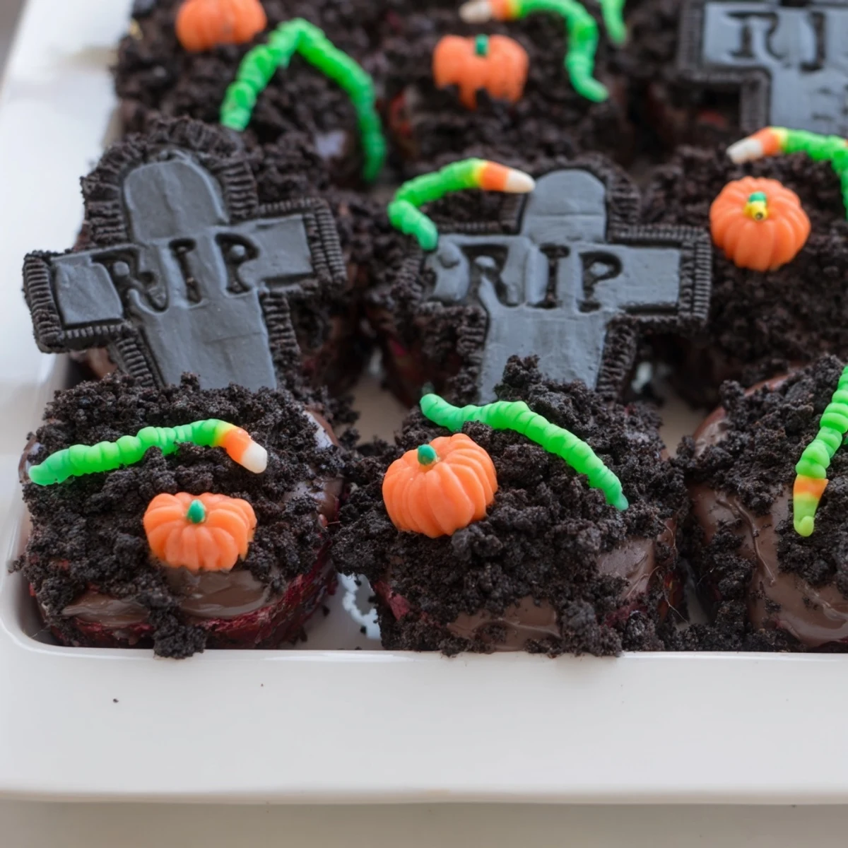 Frosted Pull Apart Graveyard Cupcakes topped with crushed cookie crumbs and gummy worms