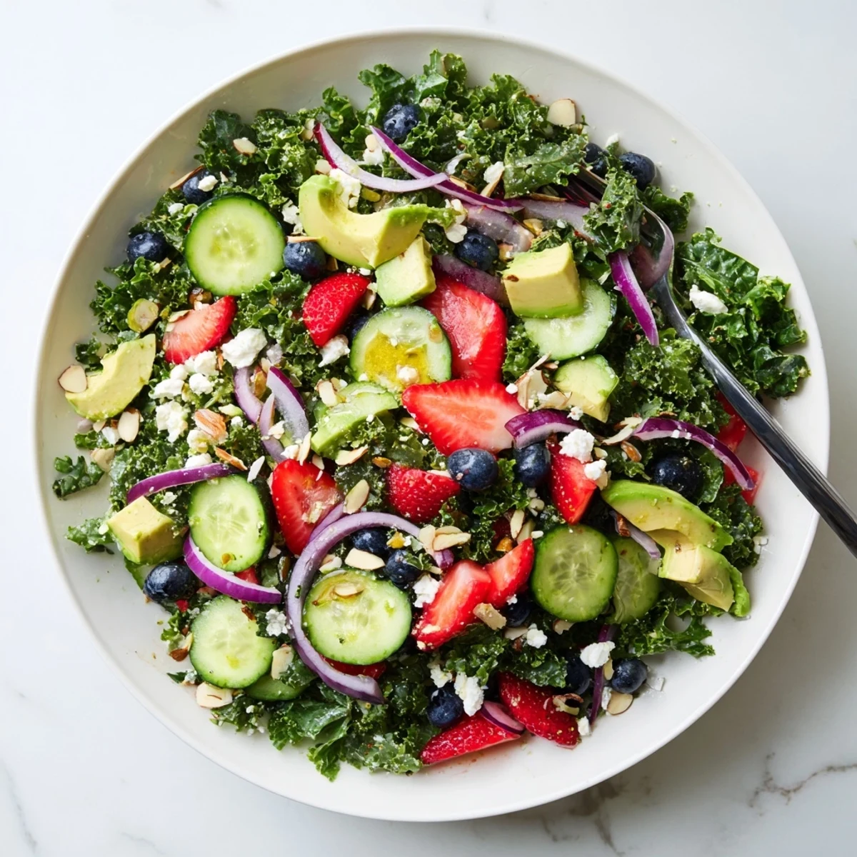 Hearty summer kale salad layered with sliced avocado, cherry tomatoes, and crunchy almonds.