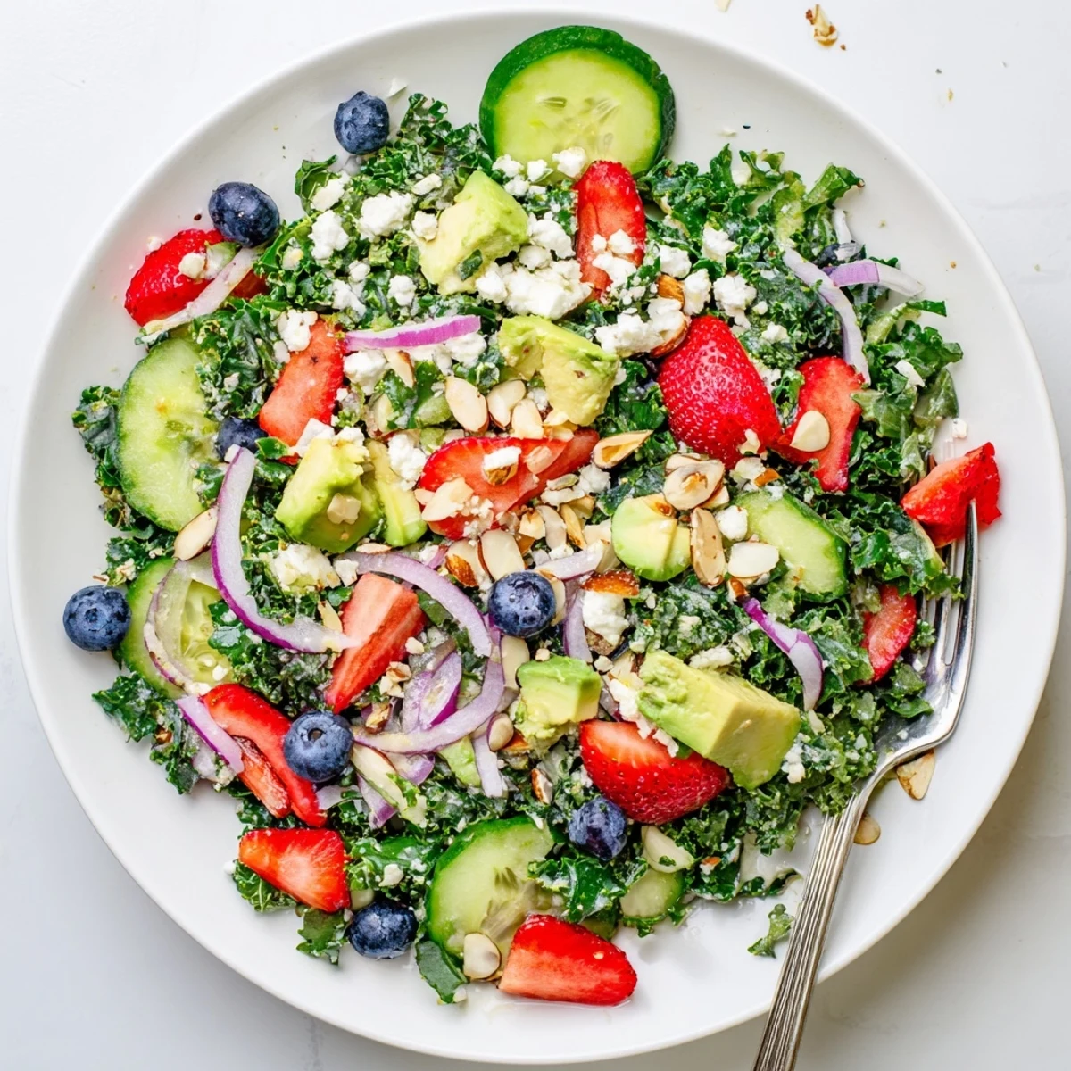 A generous portion of summer kale salad glistening with lemon-honey dressing and fresh blueberries.