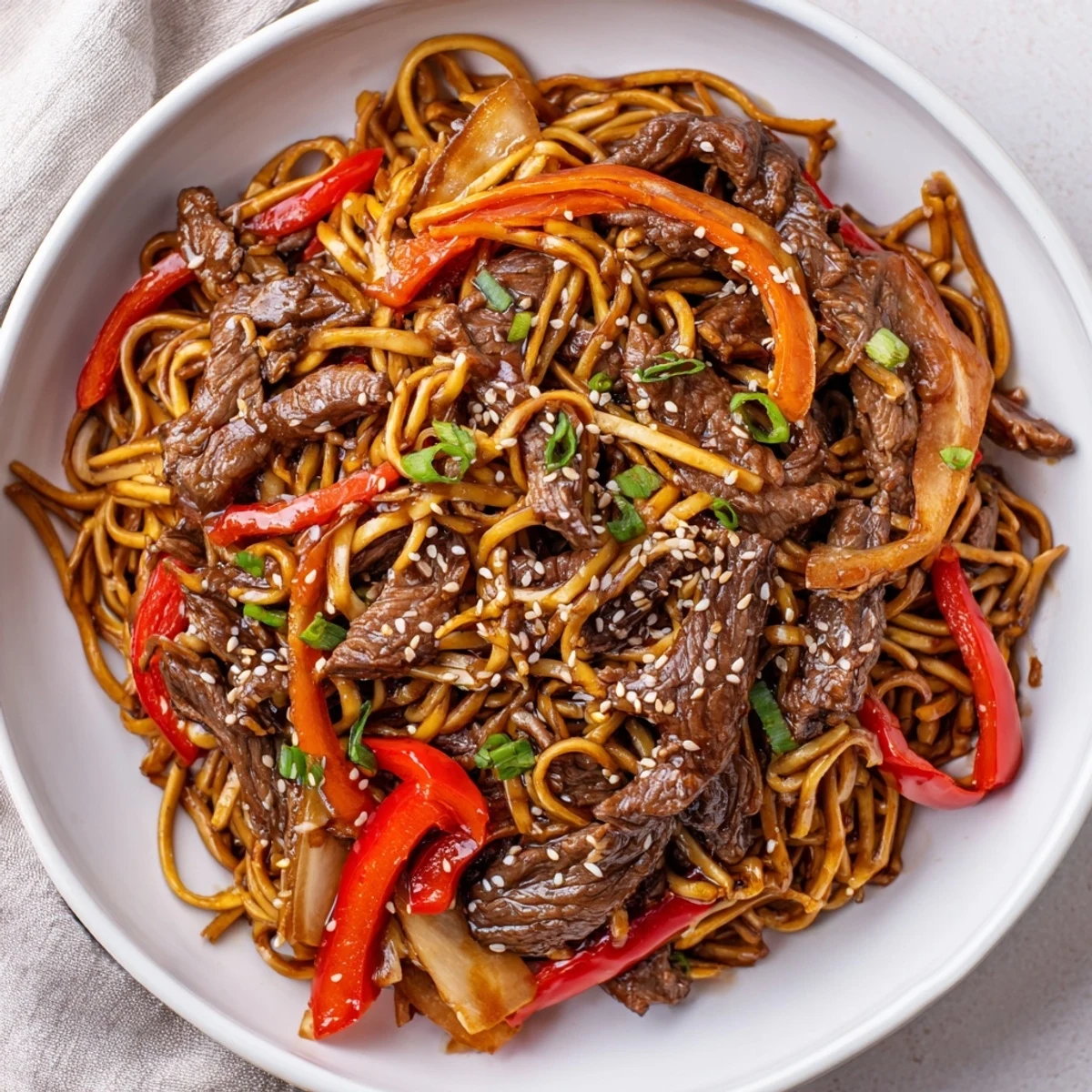 Glistening Sticky Beef Noodles tossed with scallions, sesame seeds, and rising steam