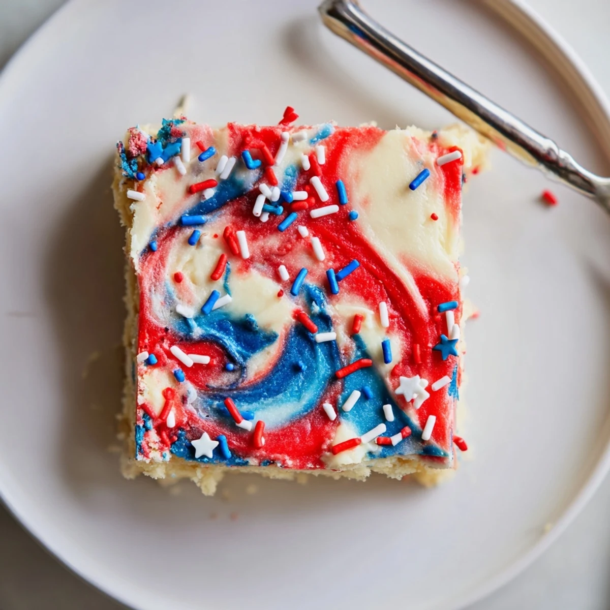 Patriotic Sugar Cookie Bars topped with swirled red, white, and blue frosting