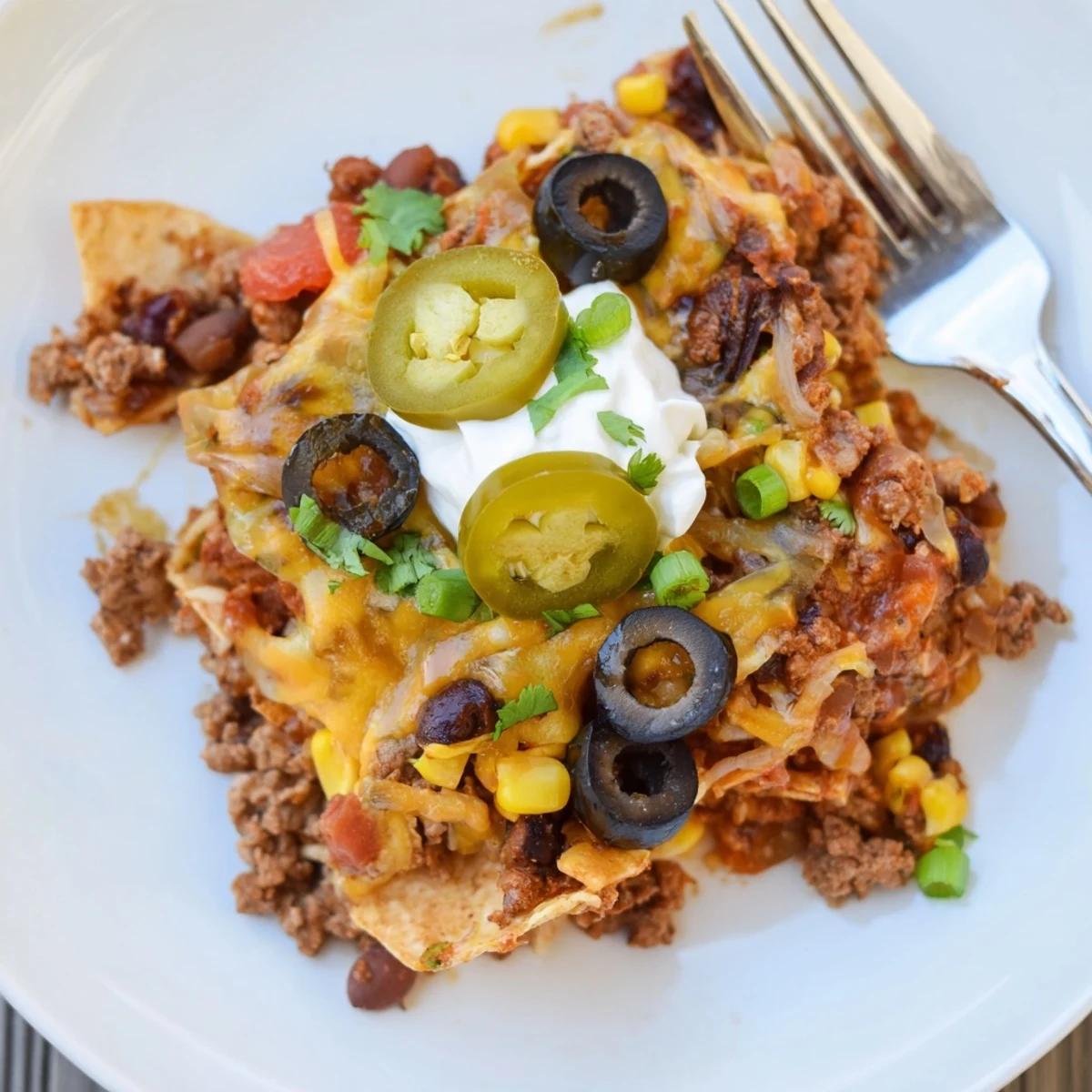 Cheesy Nacho Casserole served hot with sour cream dollop and sliced jalapeños