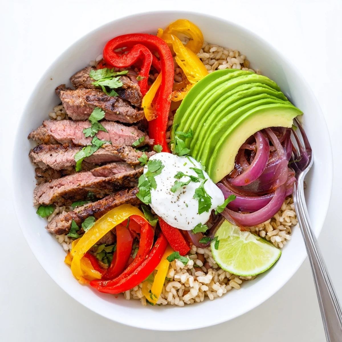 Hearty Steak Fajita Power Bowls topped with cilantro, cheddar, and lime wedges