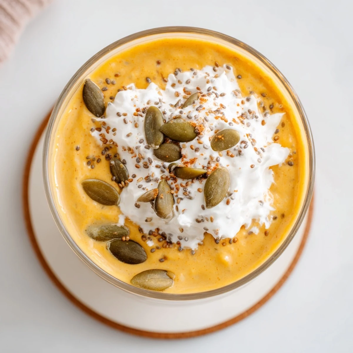 Creamy pumpkin spice drink with fluffy coconut topping and cinnamon dusting served chilled for autumn