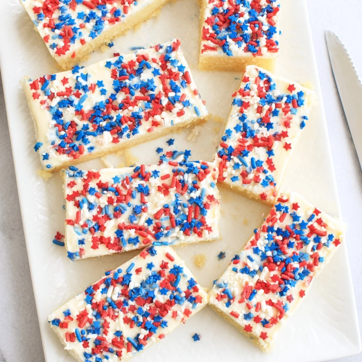 Soft 4th of July sugar cookie bars topped with creamy vanilla frosting and red white blue sprinkles