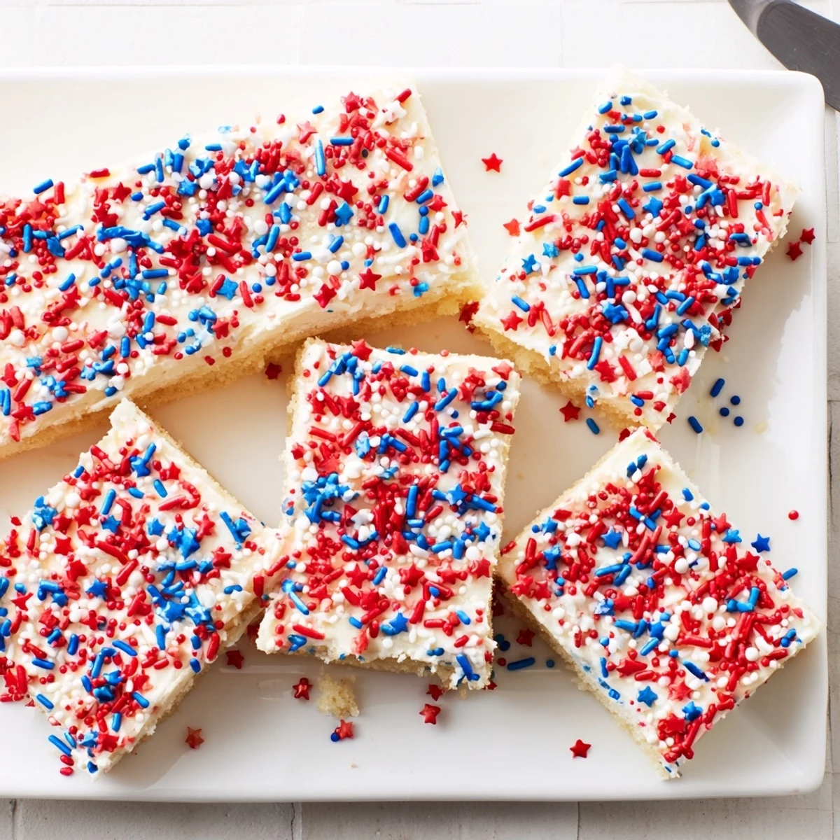 Delicious 4th of July sugar cookie bars with sweet buttercream frosting and scattered patriotic red white blue decoration