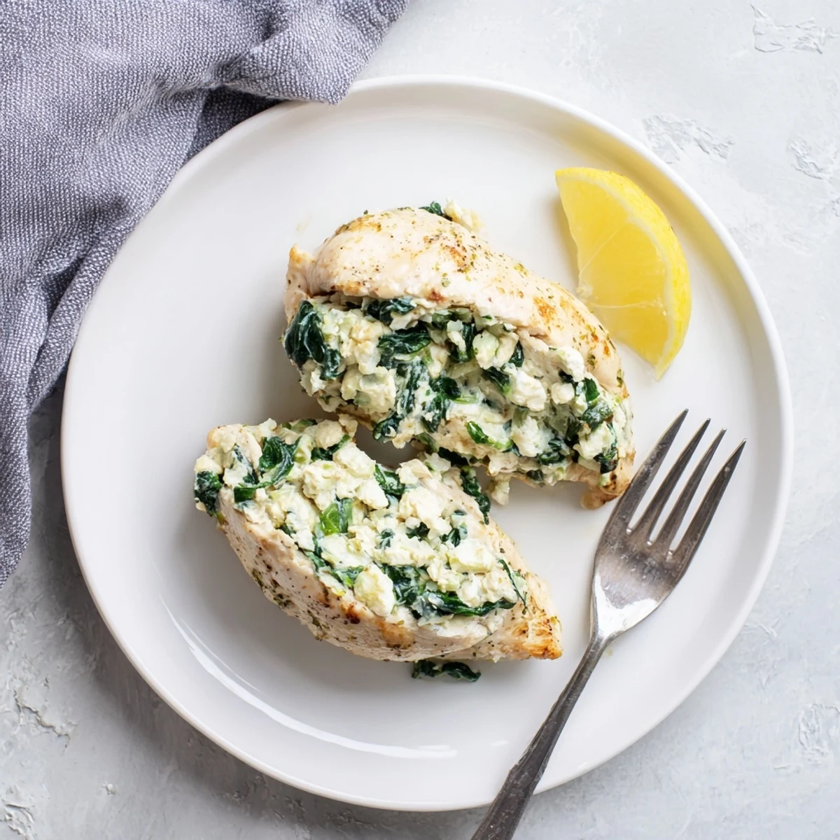 Golden baked chicken breast stuffed with spinach and feta cheese on a white plate