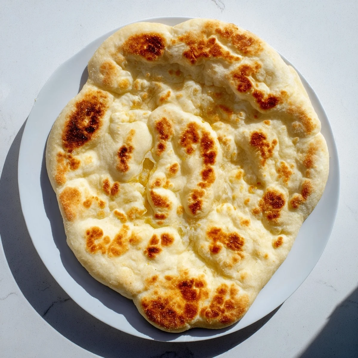 Freshly cooked Turkish Bazlama bread rounds stacked on wooden board with brushed butter top