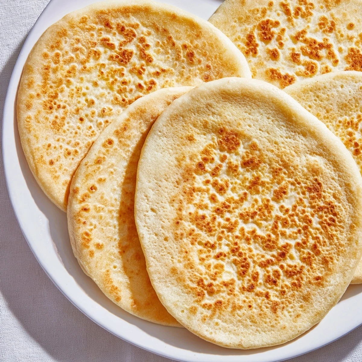 Soft Turkish Bazlama flatbread being flipped in hot skillet showing golden brown bubbly surface