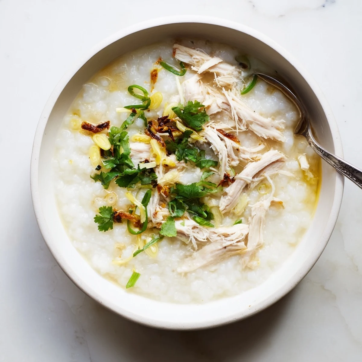 Comforting chicken congee porridge featuring tender shredded chicken and vibrant green onion slices
