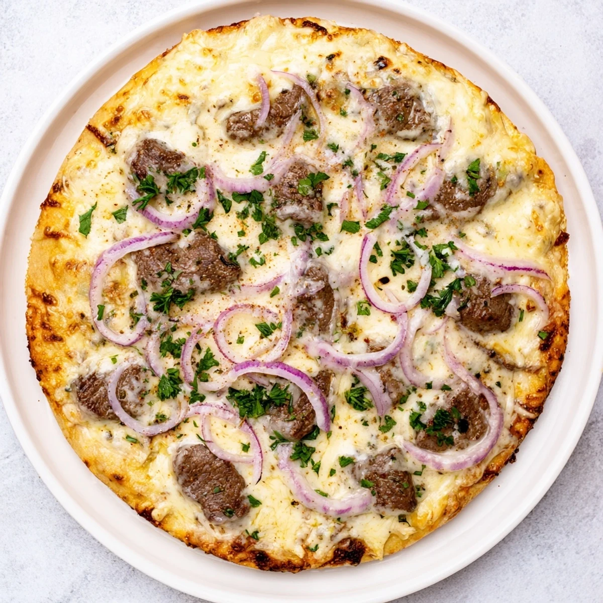 Savory slices of tender beef atop creamy garlic alfredo sauce on this golden homemade pizza