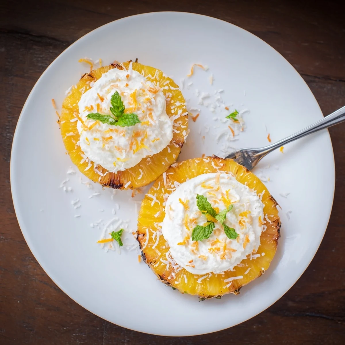 Plated Creamy Citrus Grilled Pineapple garnished with shredded coconut and fresh mint