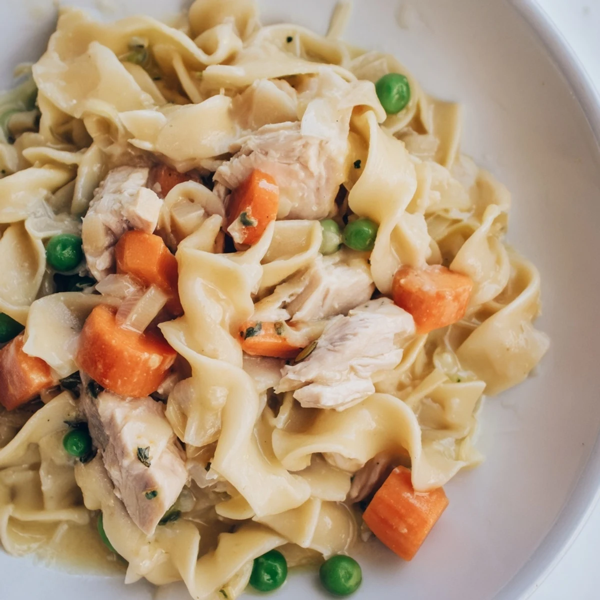 Creamy one pot chicken and noodles featuring wide egg noodles and bite-sized chicken pieces in a single skillet.