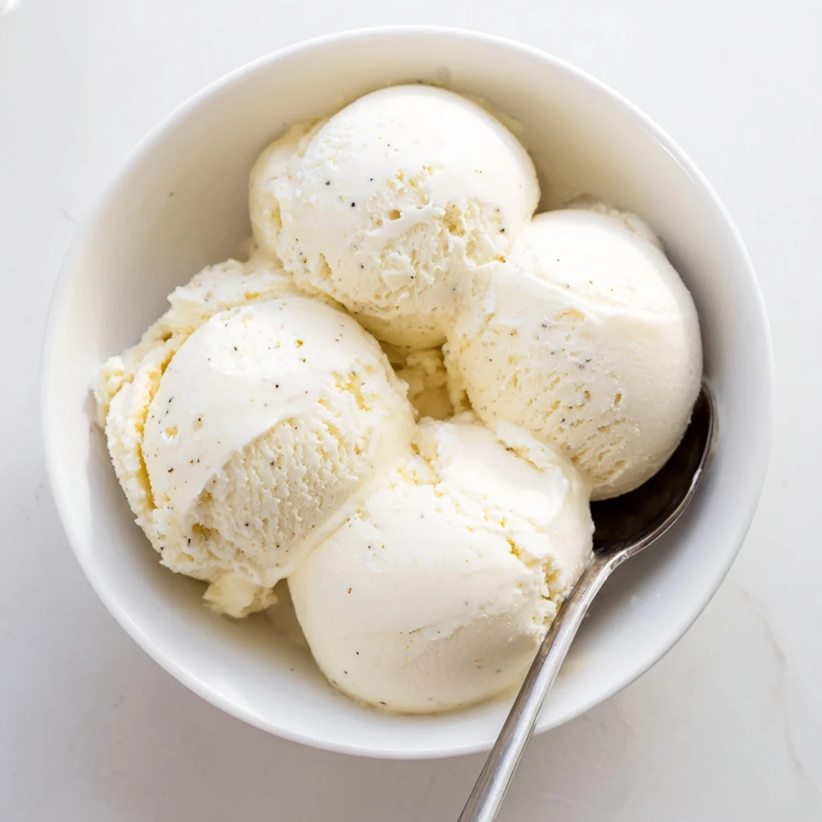 Smooth luscious homemade vanilla ice cream garnished with mint leaf and sprinkled cookie crumbs