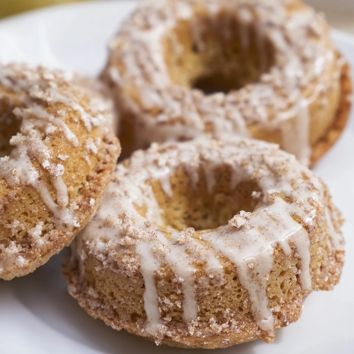 Golden brown banana bread donuts with sweet cinnamon glaze drizzled over the moist, cakey texture.