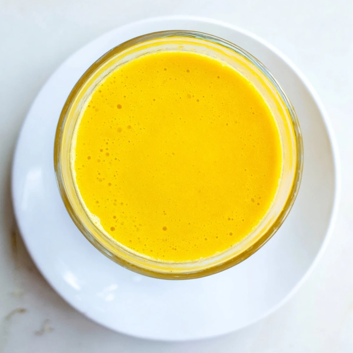 Glass of vibrant yellow Tropical Pineapple Mango Smoothie topped with fresh tropical fruit slices