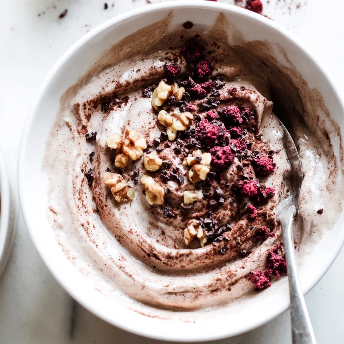 Creamy healthy nice cream scooped into bowls topped with fresh berries and chopped nuts