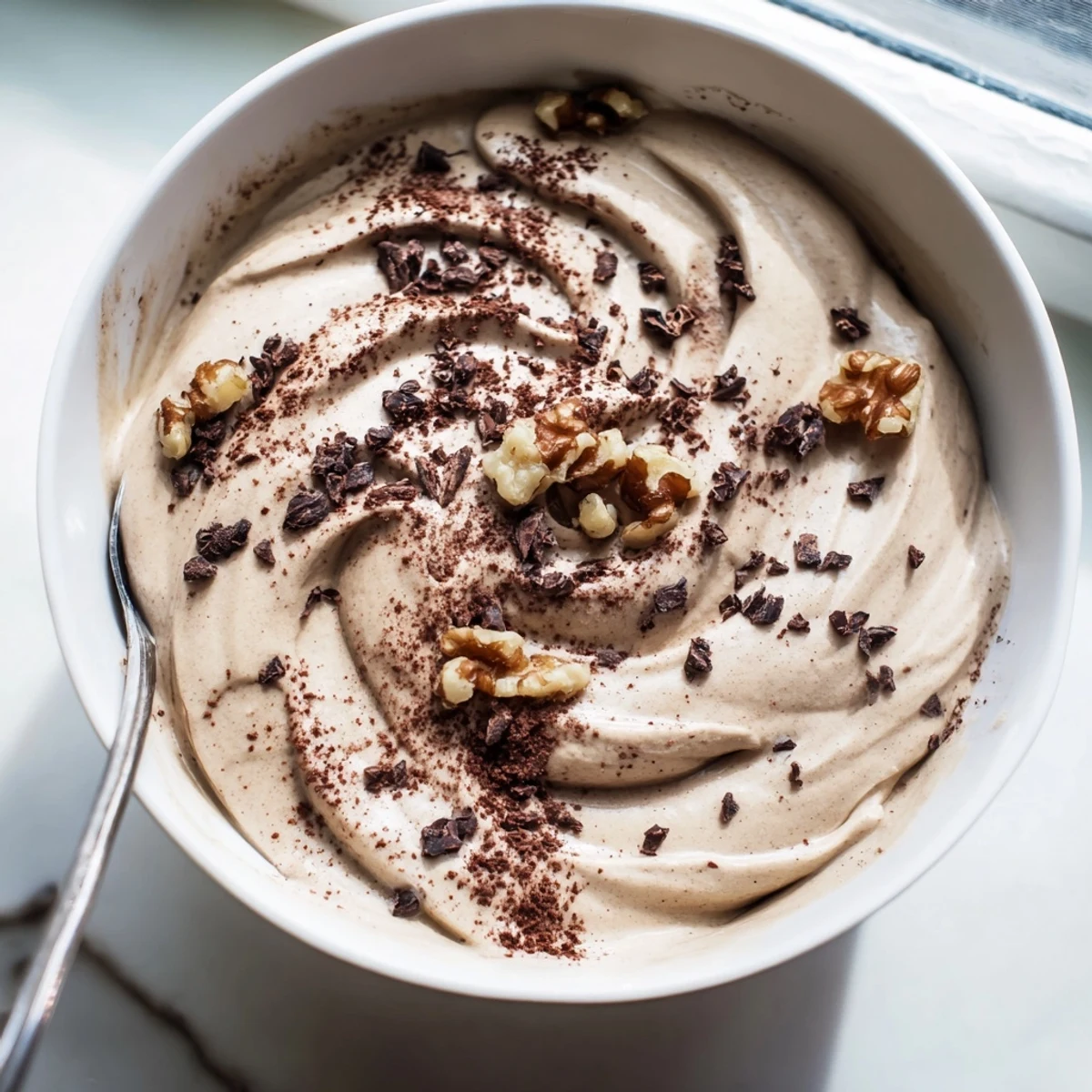 Frozen banana healthy nice cream with drizzled cocoa and cacao nibs on a wooden spoon