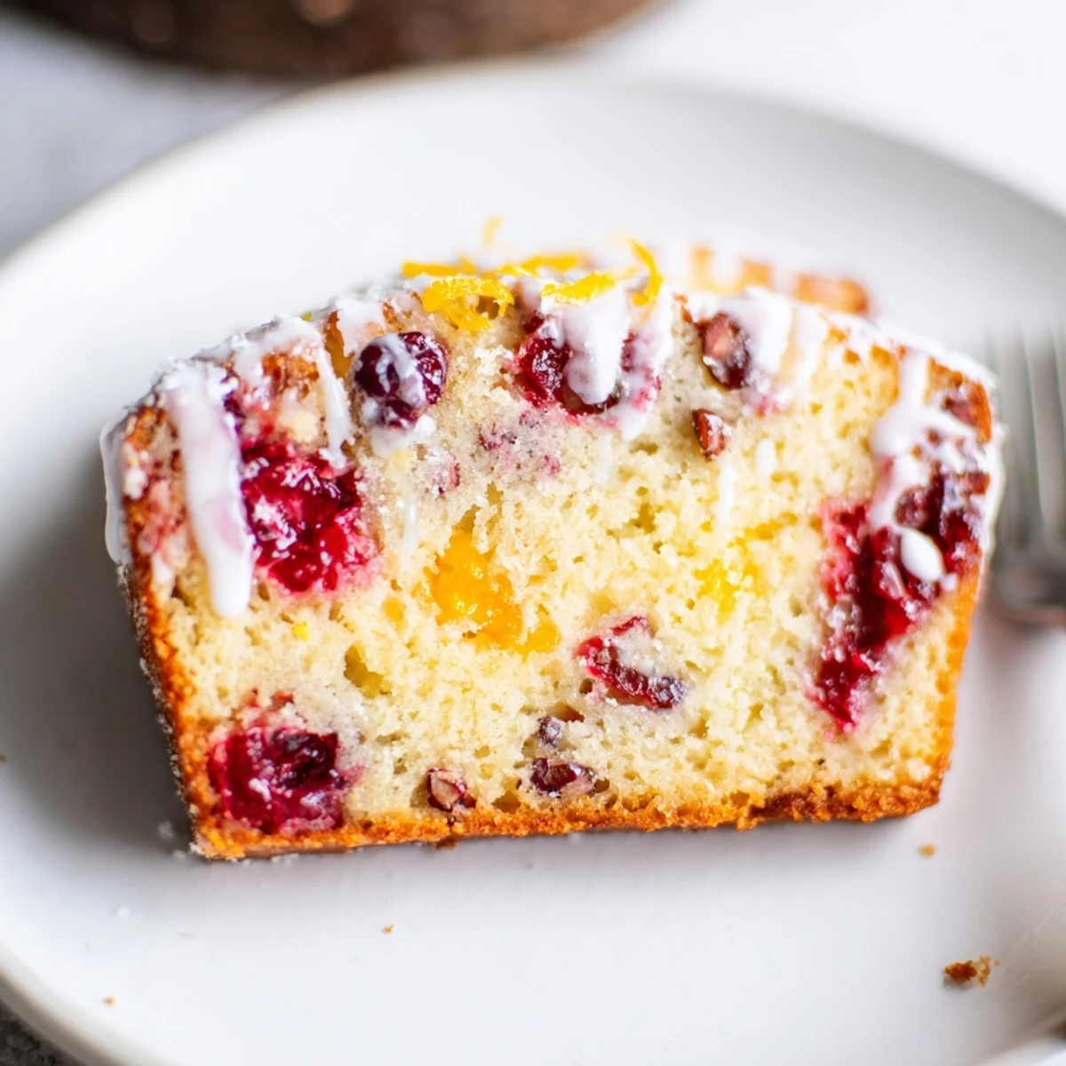 Cranberry Orange Bread warming on rack, moist slices glistening with orange glaze