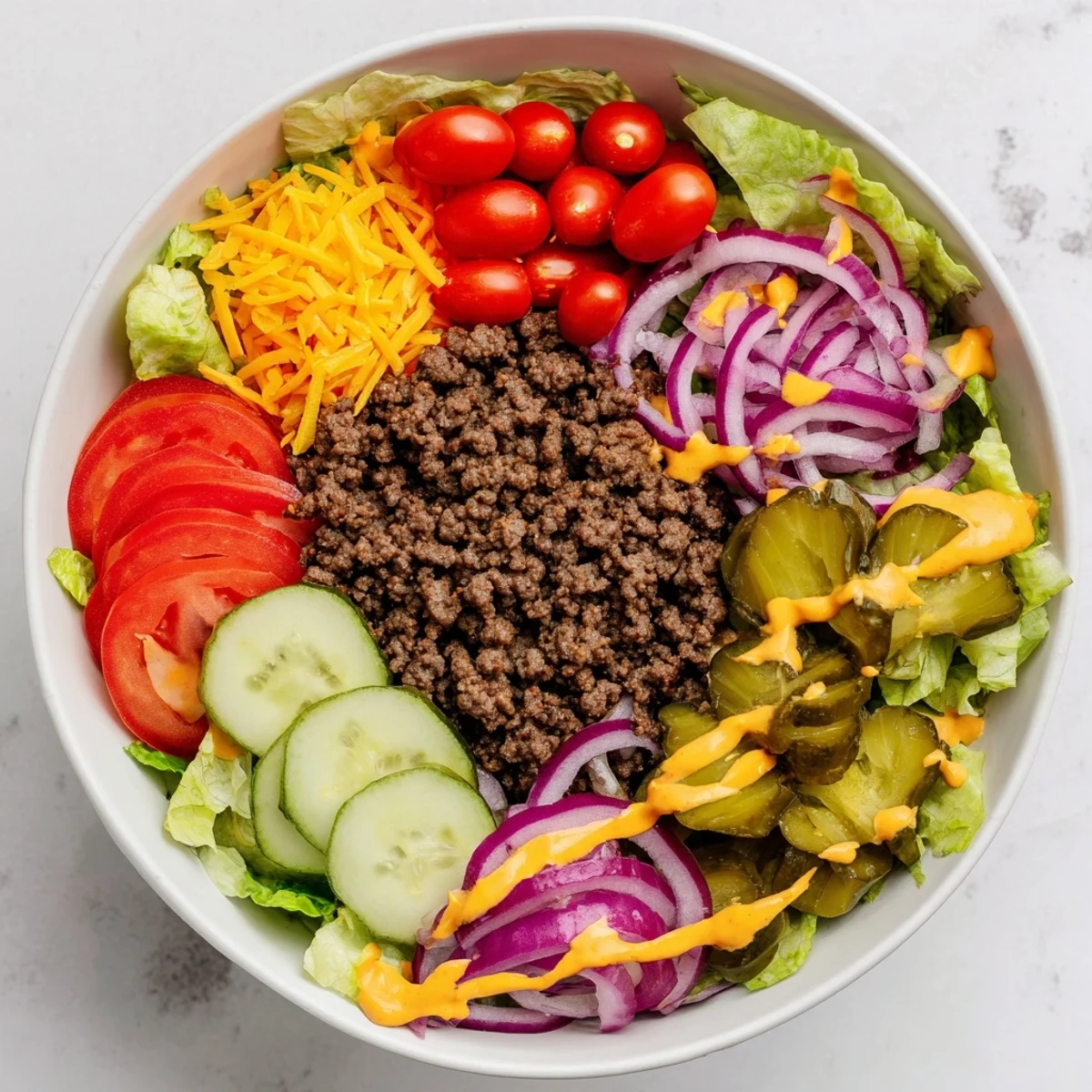 Golden brown ground beef layered over crisp shredded lettuce with fresh tomatoes and creamy burger sauce drizzled on top