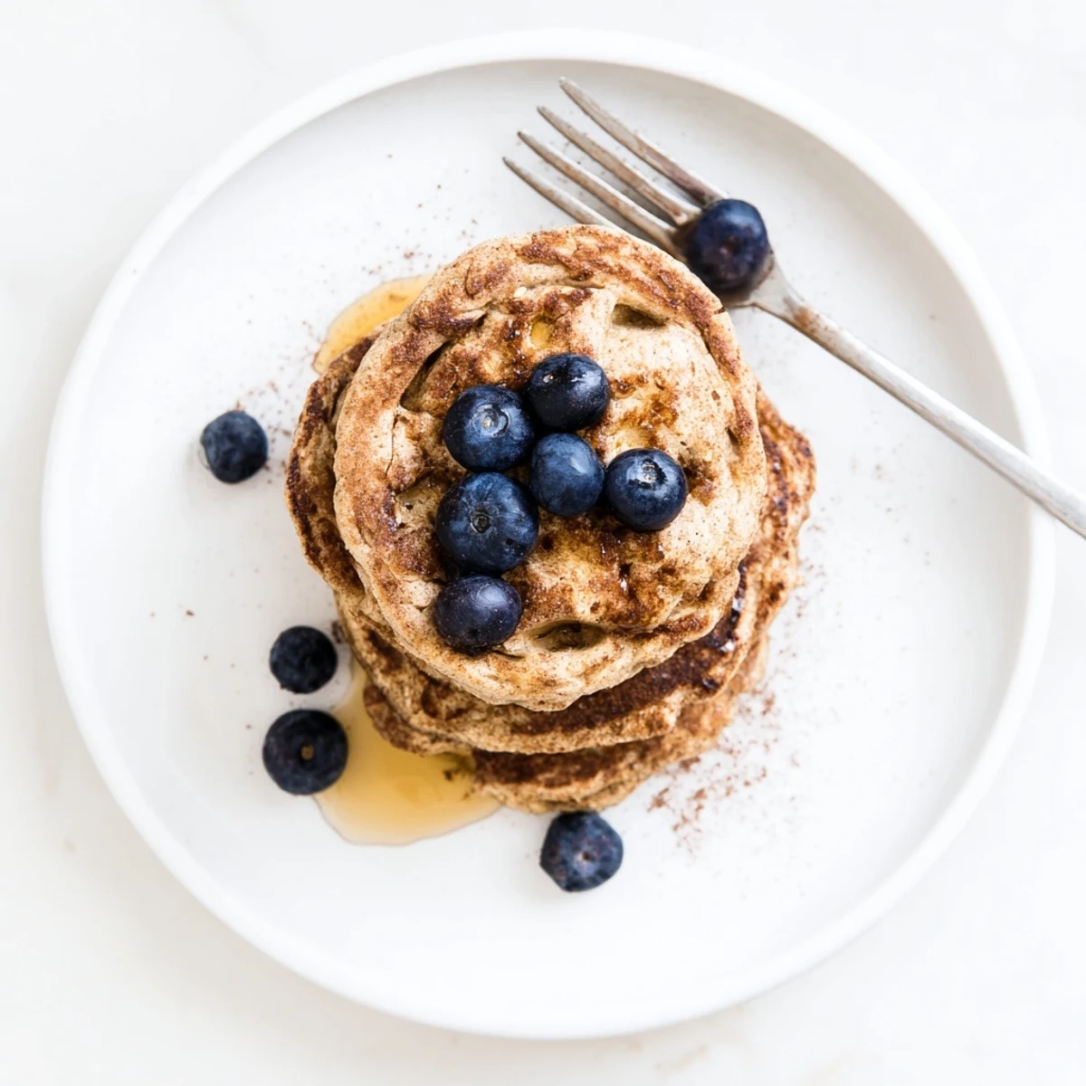 Healthy protein banana pancakes served on a white plate with mixed berries and walnuts