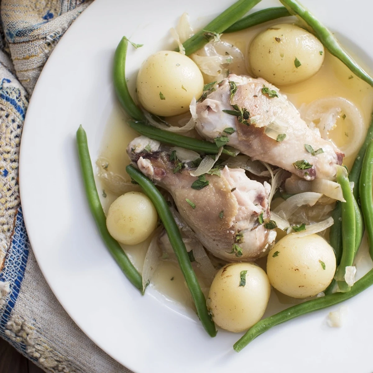 Golden slow cooker chicken and potatoes with green beans nestled in savory herb-infused broth
