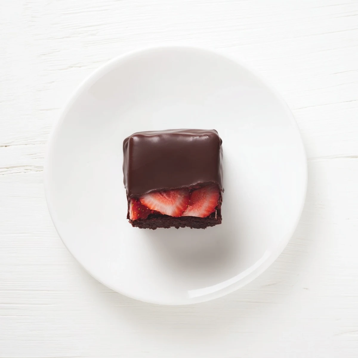 Glossy chocolate shell crowns these chocolate covered strawberry brownies with vibrant red berry slices peeking through
