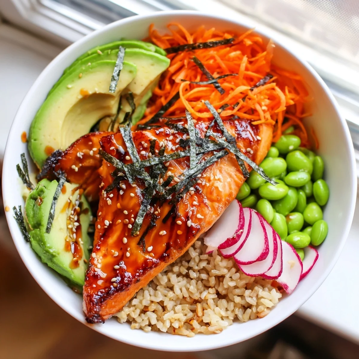 Caramelized miso salmon grain bowl topped with vibrant edamame, avocado, and sesame seeds