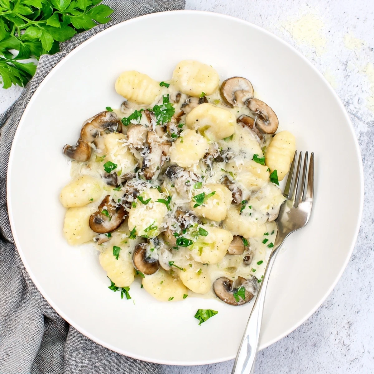 Comforting bowl of Italian mushroom gnocchi coated in a thick creamy white sauce with cheese shavings