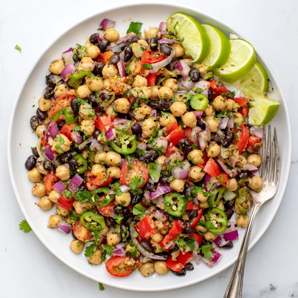 Zesty cilantro lime bean salad plated with lime wedges and extra chopped cilantro garnish for a refreshing lunch