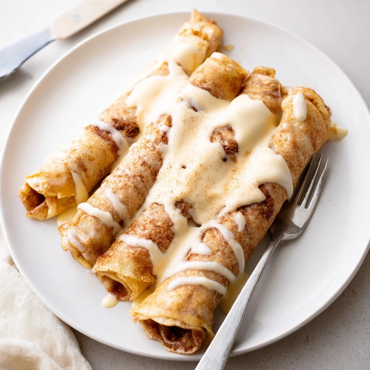 Thin cinnamon roll protein crepes rolled with creamy cinnamon filling and sweet vanilla glaze