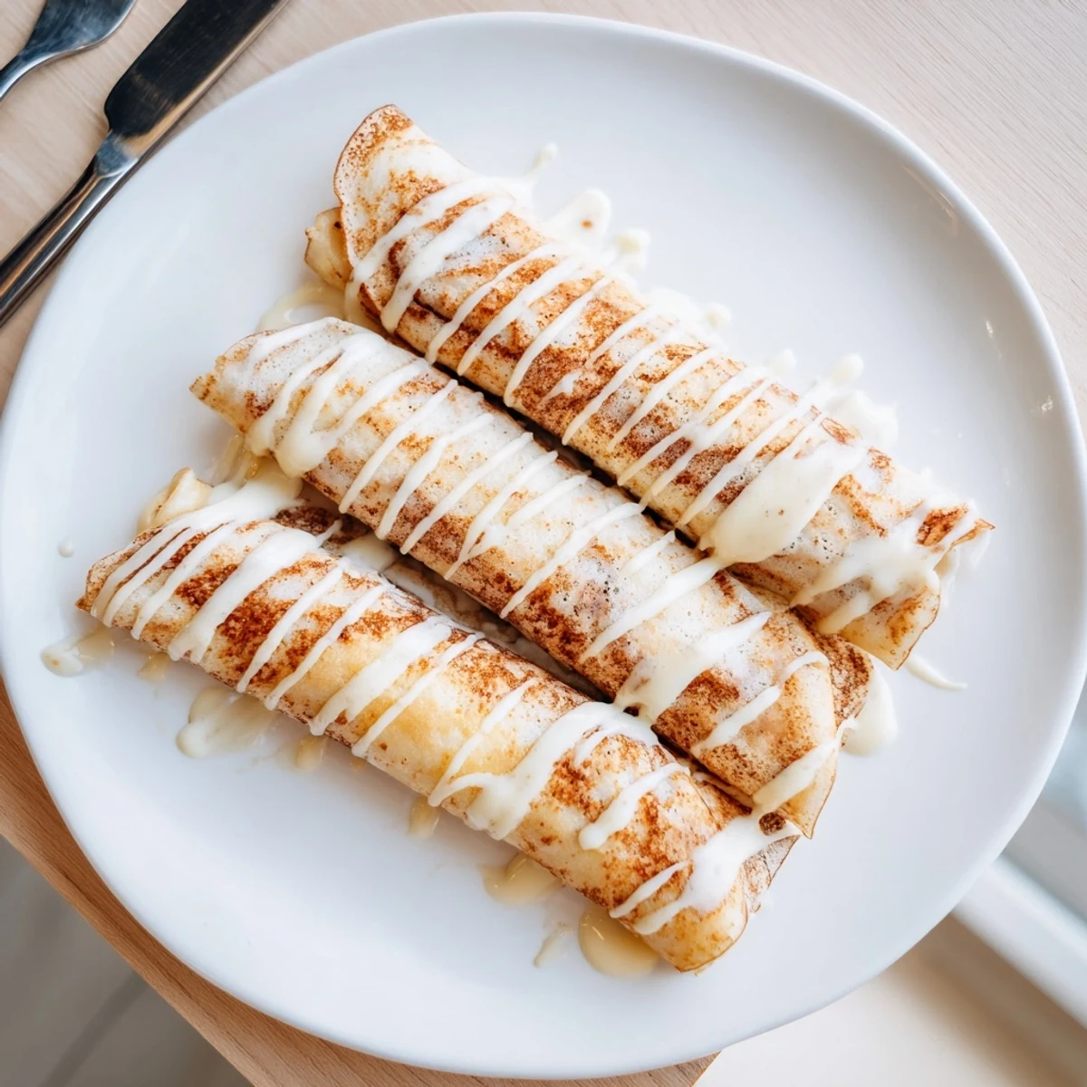 Golden crepes filled with spiced cream cheese swirl drizzled with powdered sugar glaze