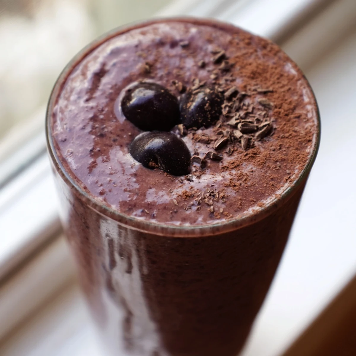 Rich chocolate cherry protein shake garnished with cocoa dust and ripe cherry on top