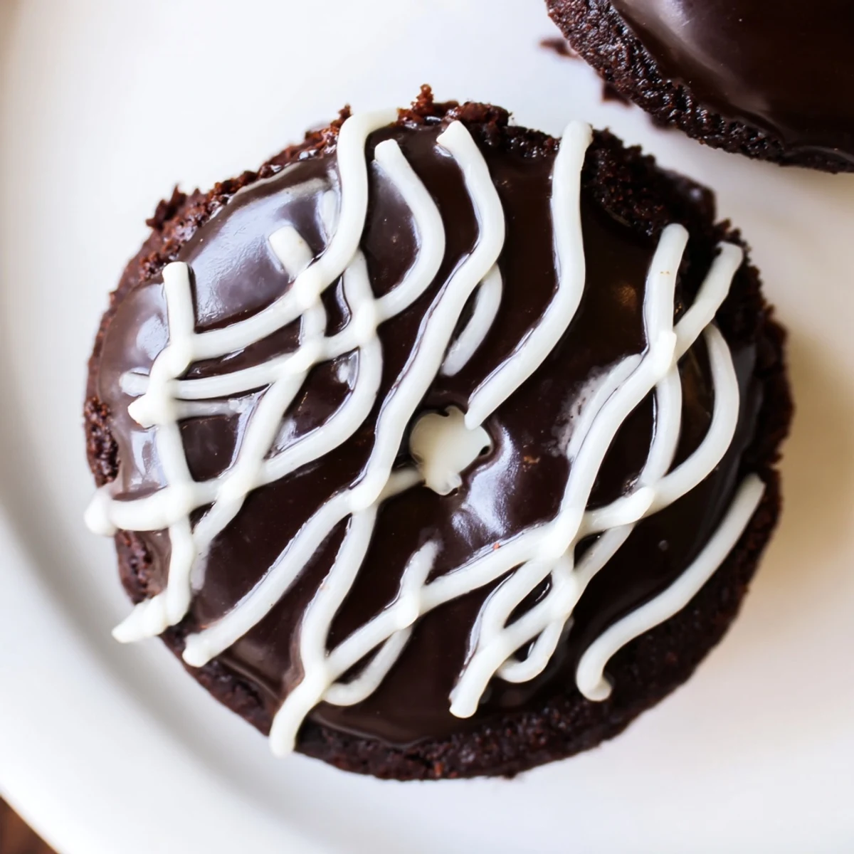 Homemade Hostess Cupcakes with glossy ganache, creamy marshmallow filling, and iconic white swirls on a rustic plate