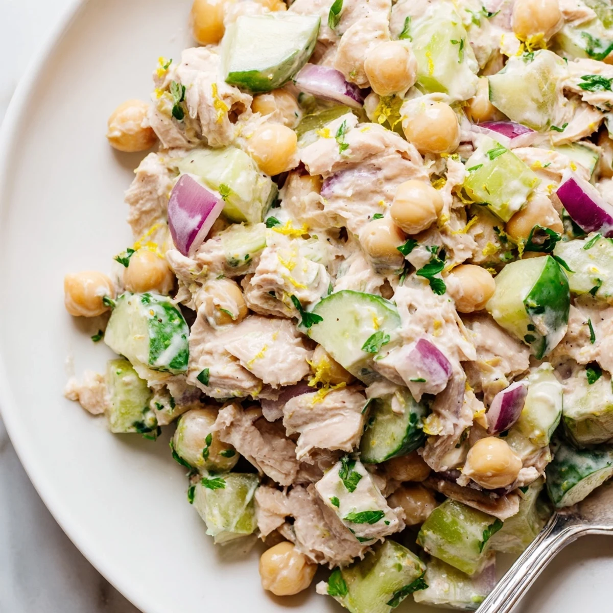 Creamy tuna chickpea cucumber salad served in a rustic bowl with fresh herbs