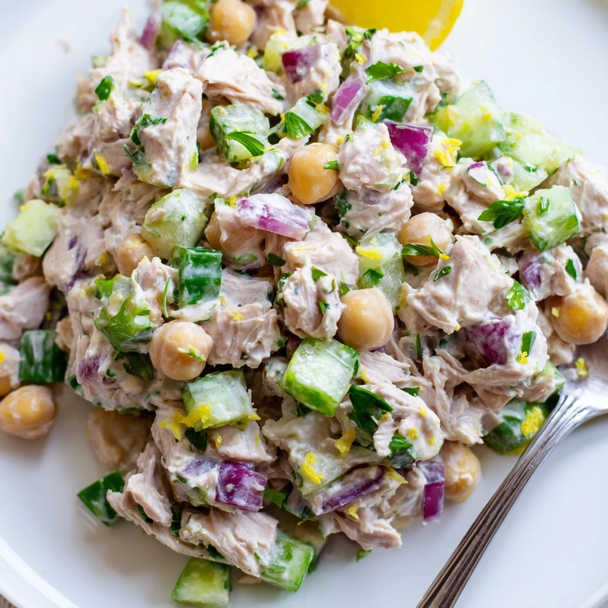 A vibrant creamy tuna chickpea cucumber salad scooped onto crisp lettuce leaves
