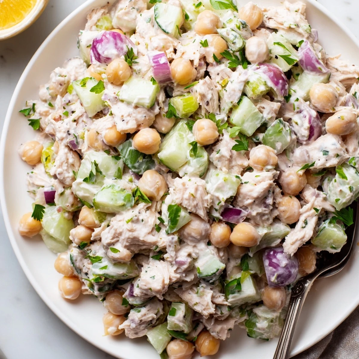 Tuna chickpea cucumber salad topped with cherry tomatoes and a creamy dressing