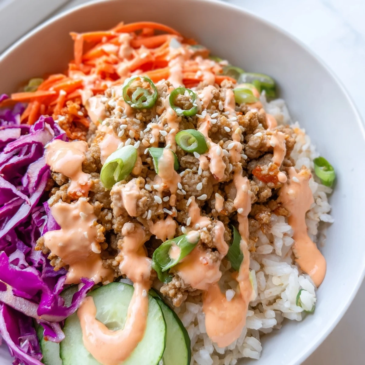 Ground Turkey Rice Bowls topped with colorful crisp vegetables and drizzled Bang Bang sauce
