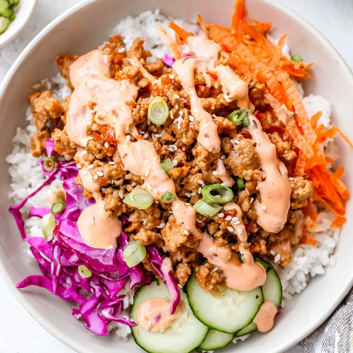 Ground Turkey Rice Bowls garnished with sesame seeds cucumber and creamy Bang Bang drizzle