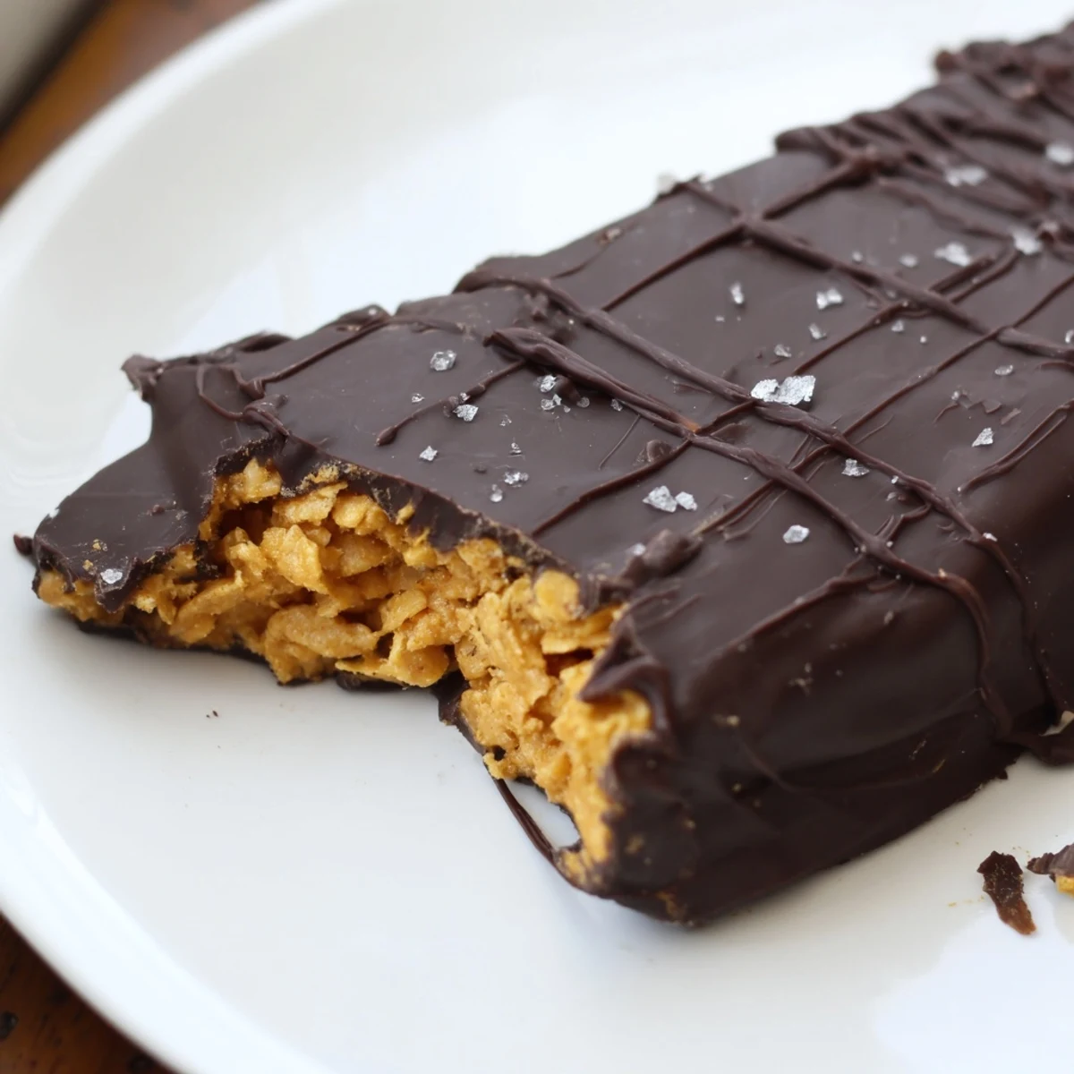 Crunchy healthy homemade Butterfingers coated in glossy dark chocolate on a parchment-lined tray