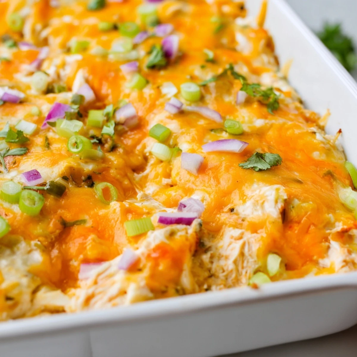 Creamy jalapeno buffalo chicken casserole topped with green onions in a baking dish