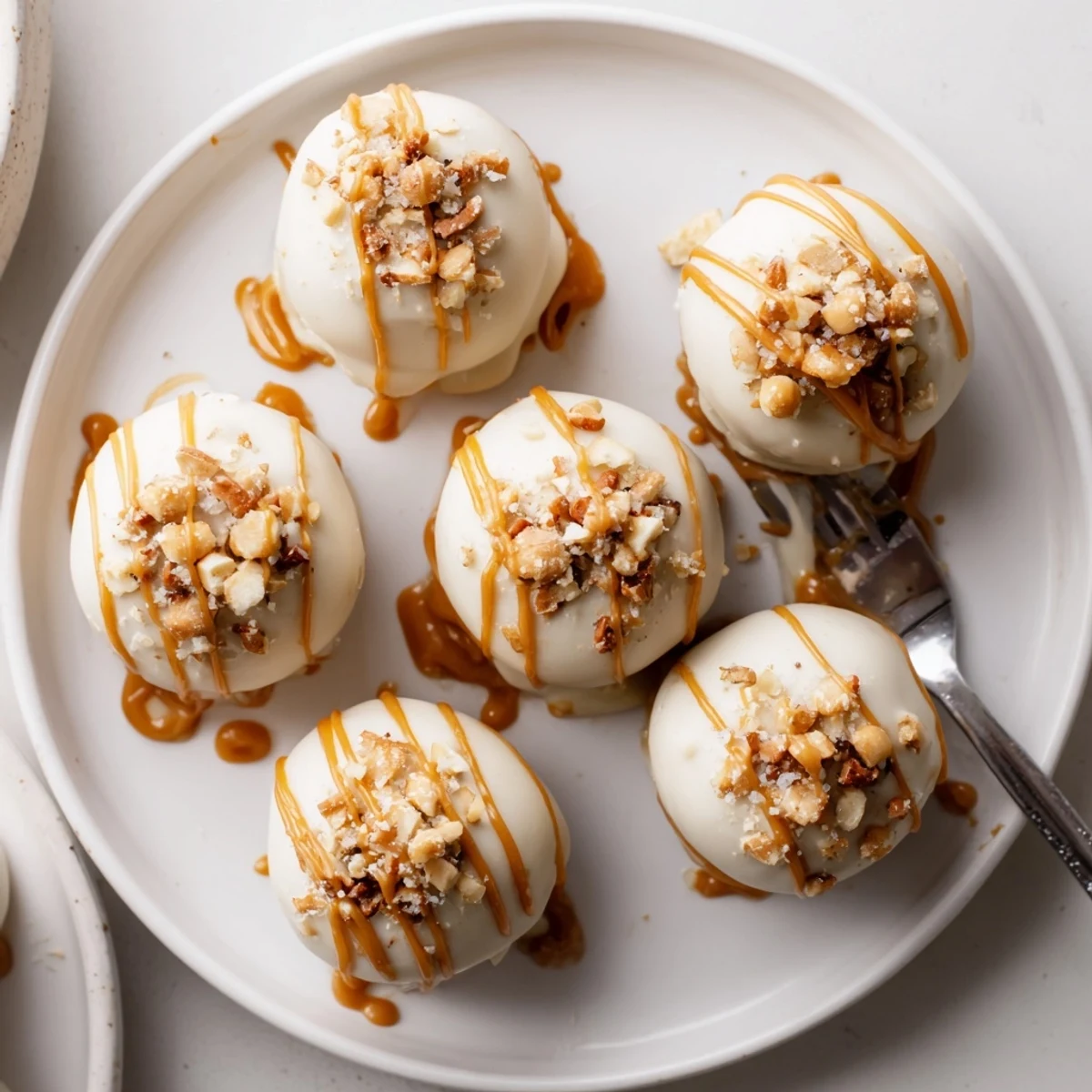 Golden-dipped salted caramel pretzel cheesecake balls topped with crushed pretzels and flaky salt